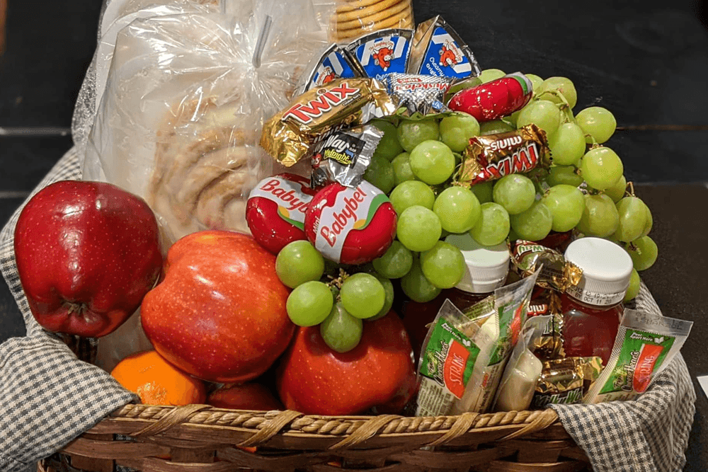 Apples, oranges, and grapes with candy and cheese snacks in a gift basket