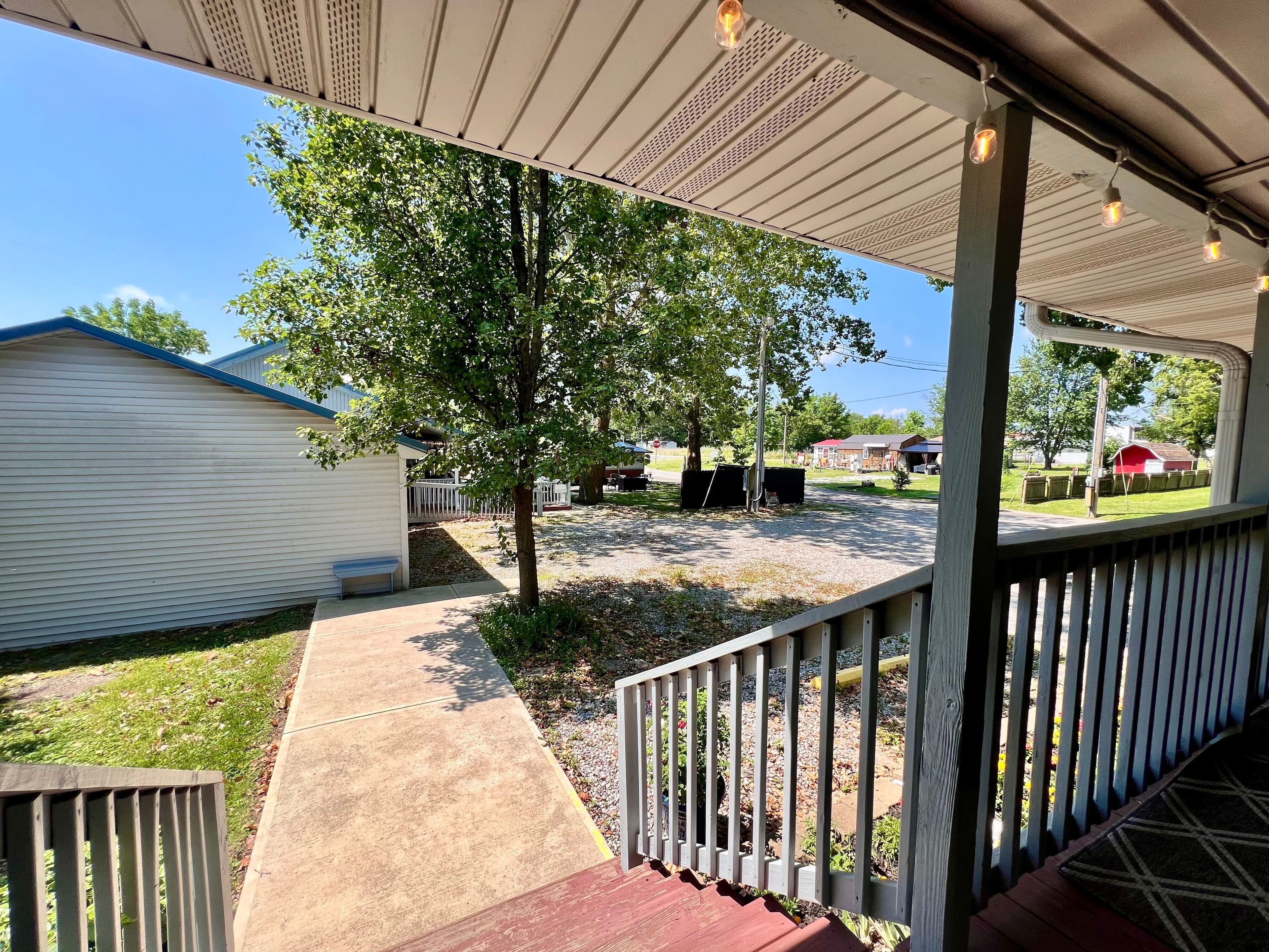 Expansive outdoor patio with hanging ferns, benches, tables, outdoor patio table with umbrella and hanging lights